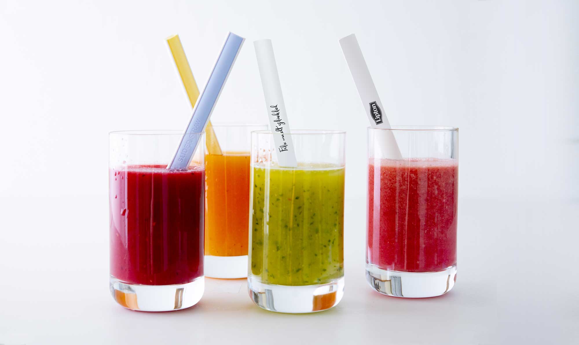 Vier bunte Sliderstraw-Mehrweg-Strohhalme in Gläsern mit Smoothies.